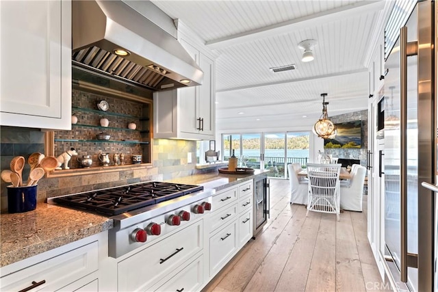 kitchen with beverage cooler, wall chimney exhaust hood, white cabinetry, and stainless steel appliances
