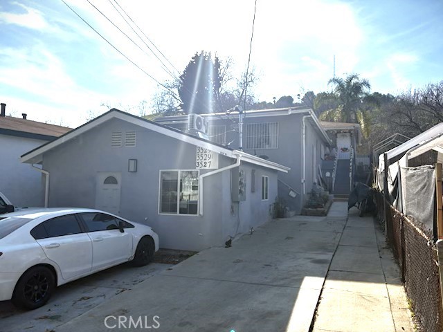 view of side of property with stucco siding and fence