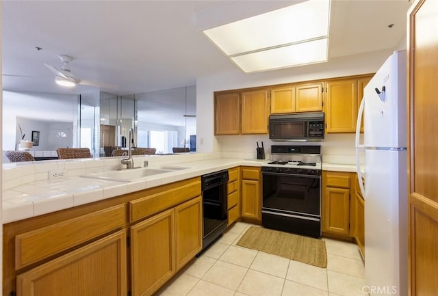 kitchen with ceiling fan, brown cabinets, a sink, light tile patterned floors, and black appliances