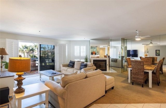 living room featuring a ceiling fan, light carpet, a wealth of natural light, and a fireplace