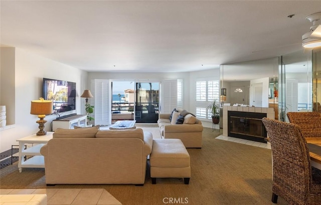 living area featuring light tile patterned flooring, light colored carpet, and a tile fireplace