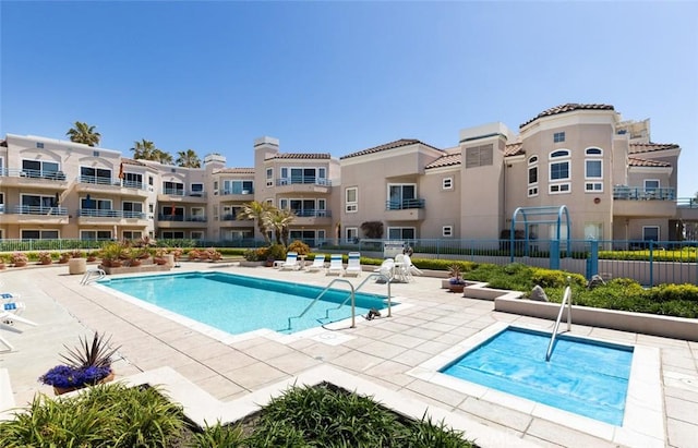community pool with fence and a patio area