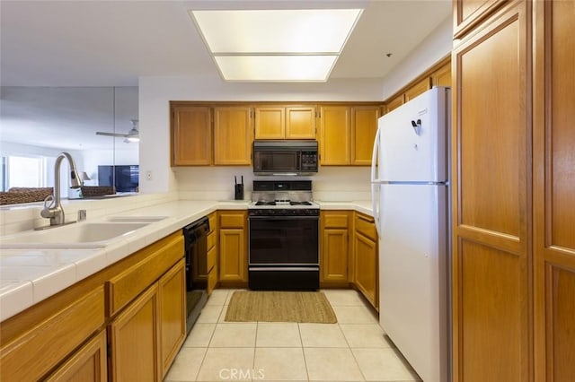 kitchen with a sink, light tile patterned floors, black appliances, and brown cabinets