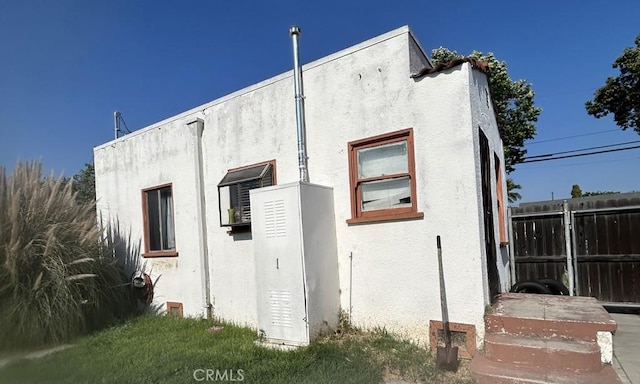 view of side of property featuring fence and stucco siding