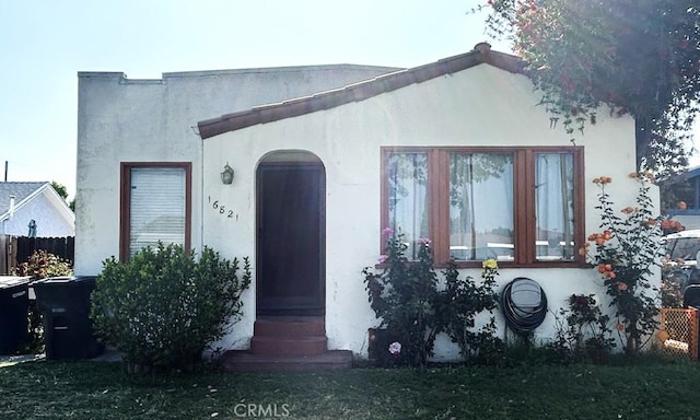 mediterranean / spanish-style house with entry steps, fence, and stucco siding