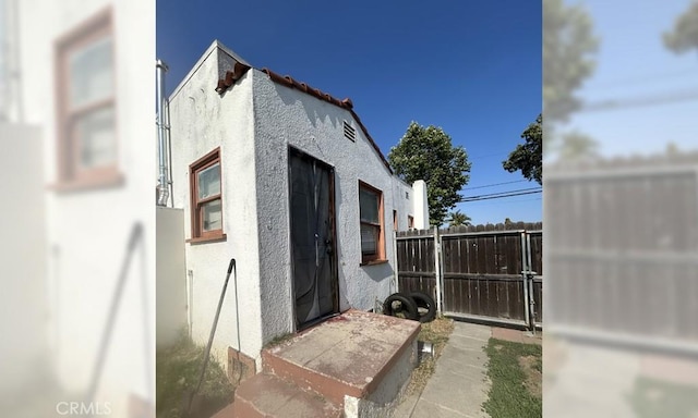 view of side of property with fence and stucco siding