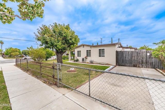 view of front of house featuring stucco siding, a fenced front yard, and a front lawn