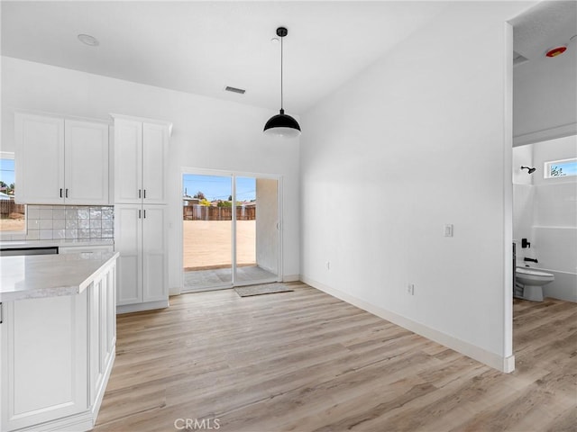 unfurnished dining area featuring baseboards, visible vents, light wood finished floors, and a wealth of natural light