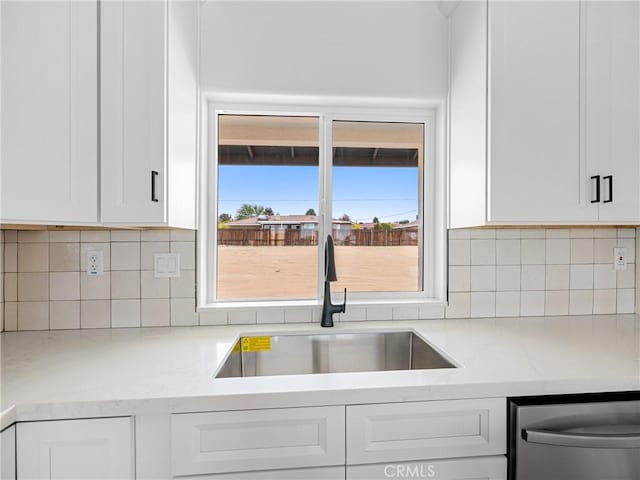 kitchen featuring white cabinetry, tasteful backsplash, a sink, and dishwasher