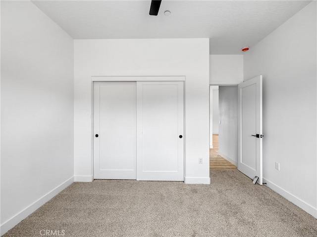 unfurnished bedroom with carpet floors, baseboards, and a closet