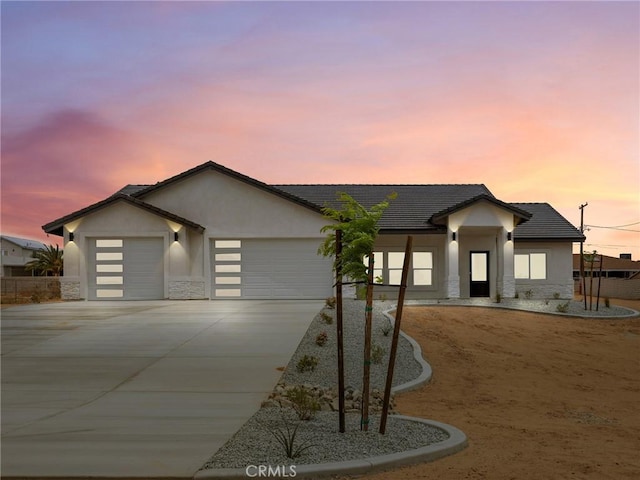 contemporary house featuring a garage, stucco siding, driveway, and stone siding