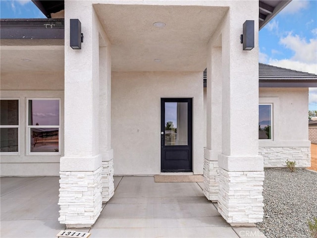 entrance to property featuring stucco siding and stone siding
