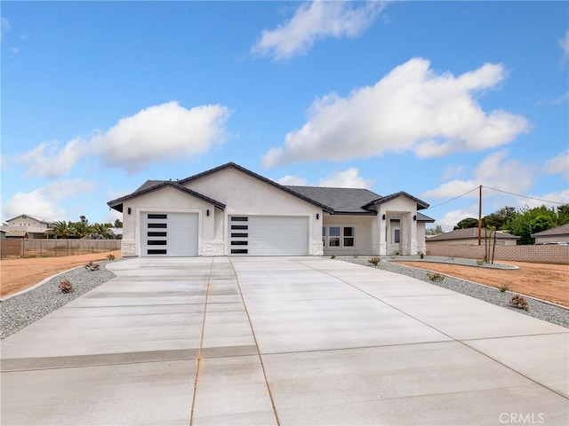 view of front of home with a garage, fence, stone siding, stucco siding, and concrete driveway