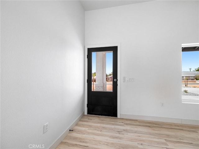 doorway to outside featuring baseboards and wood finished floors