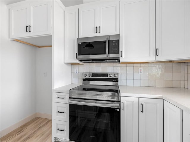 kitchen with light countertops, stainless steel appliances, baseboards, light wood-type flooring, and tasteful backsplash