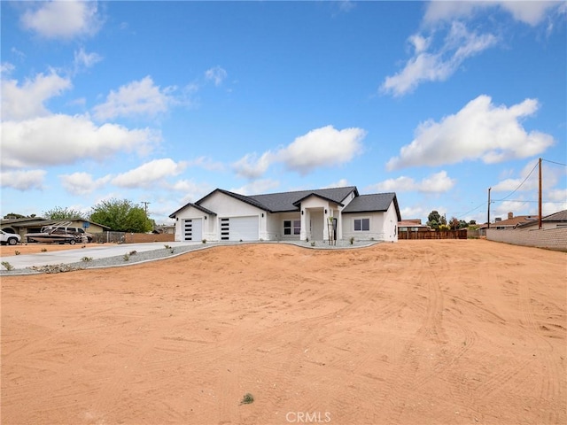 view of front of home with stucco siding, a garage, fence, and driveway