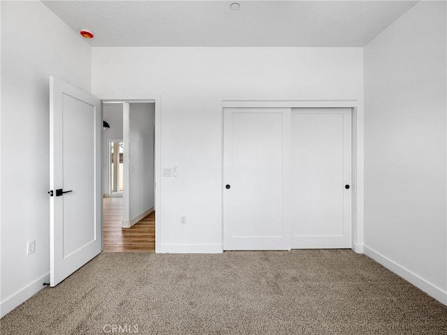 unfurnished bedroom featuring carpet floors, baseboards, and a closet
