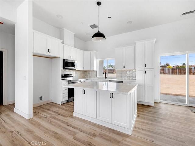 kitchen featuring visible vents, a sink, a kitchen island, and stainless steel appliances