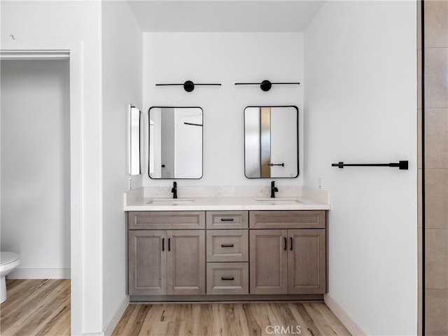 full bath with a sink, toilet, and wood finished floors