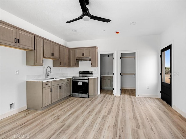 kitchen with a sink, light countertops, baseboards, under cabinet range hood, and stainless steel electric stove
