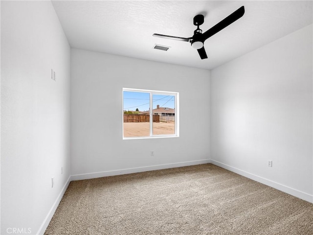 carpeted empty room with baseboards, a ceiling fan, and visible vents
