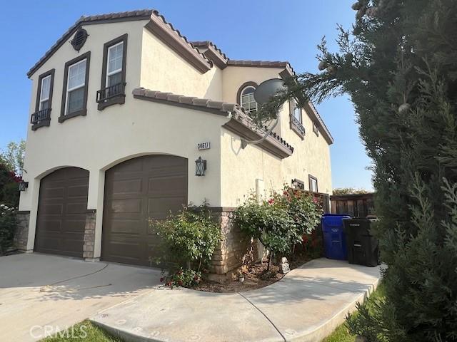 mediterranean / spanish home with concrete driveway, a tiled roof, an attached garage, and stucco siding