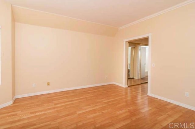 spare room featuring crown molding, light wood-style flooring, and baseboards