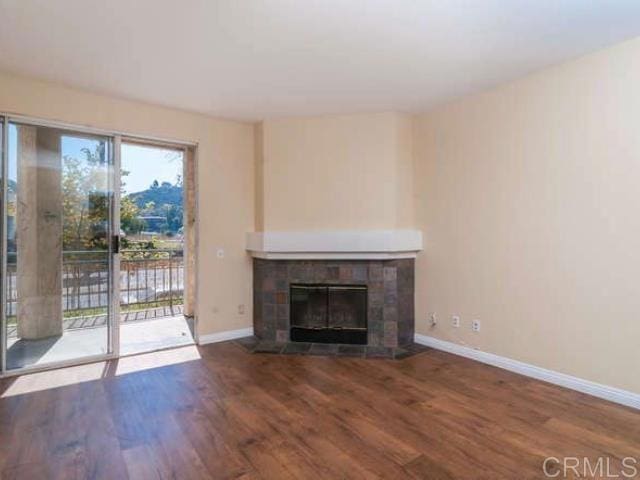 unfurnished living room featuring baseboards, wood finished floors, and a fireplace