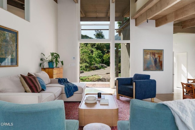 living room with a high ceiling, beamed ceiling, and wood finished floors