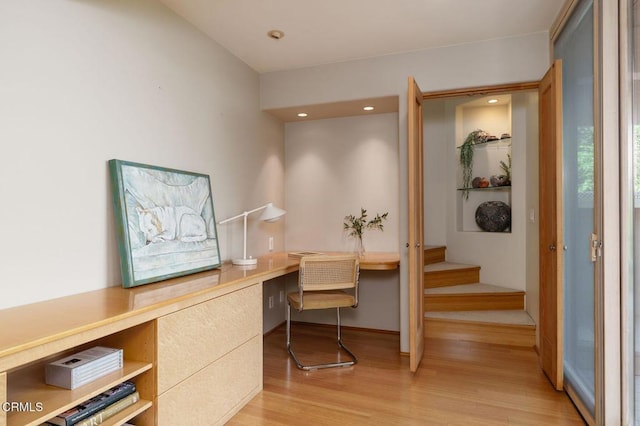 office area featuring light wood finished floors, built in desk, and recessed lighting