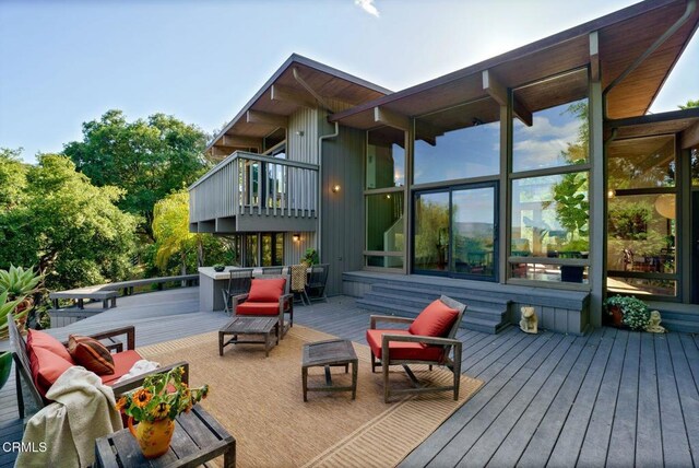 back of house featuring an outdoor living space, a deck, and a balcony