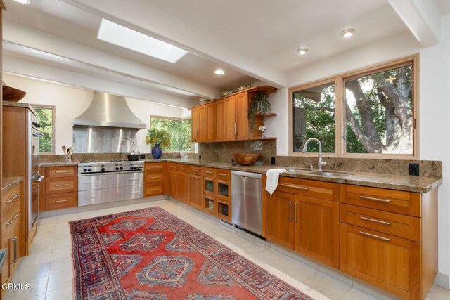 kitchen with dishwasher, wall chimney range hood, a sink, tasteful backsplash, and open shelves