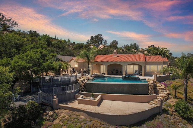 944 Rainbow Crest Rd, Fallbrook, CA 92028 - back of house at dusk with an in-ground hot tub, a tile roof, an outdoor pool, a patio, and a chimney