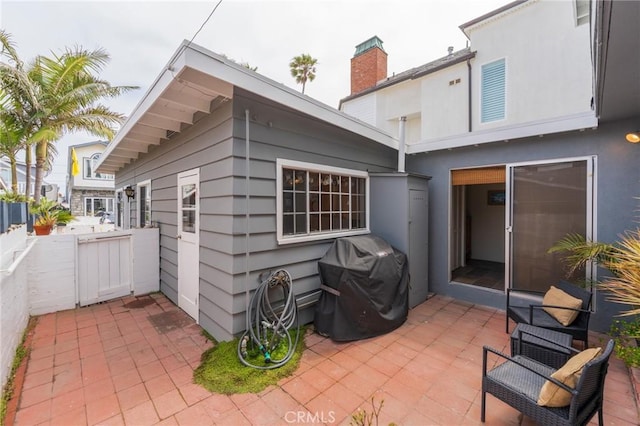 rear view of house with a patio area, a chimney, fence, and stucco siding