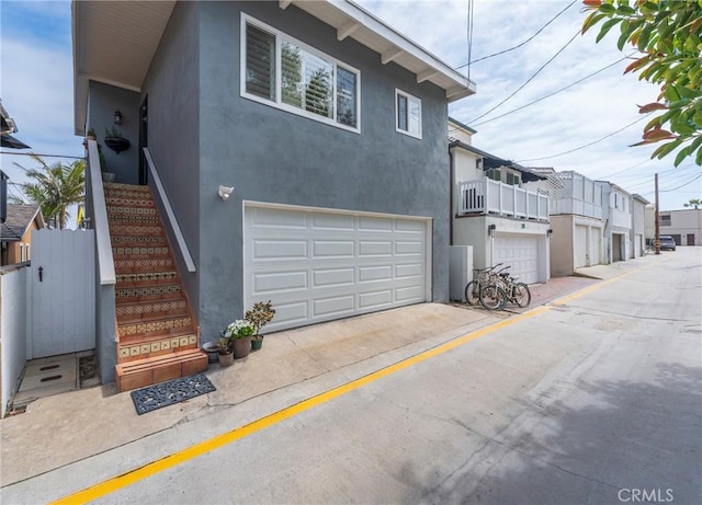 view of front of house featuring an attached garage, stairway, and stucco siding