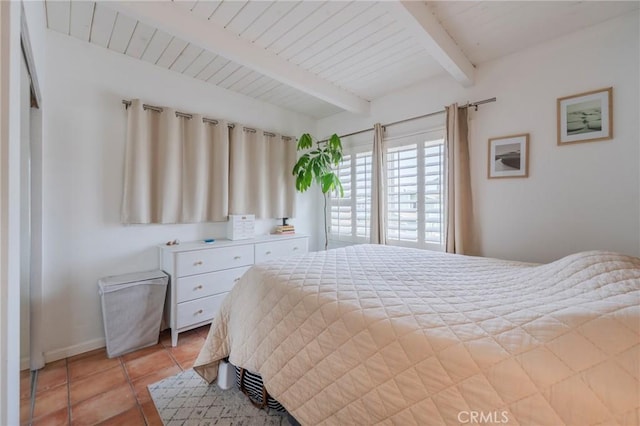 bedroom featuring beam ceiling, light tile patterned floors, and baseboards