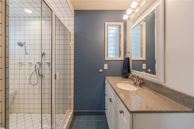 bathroom with a shower stall, vanity, tile patterned flooring, and toilet