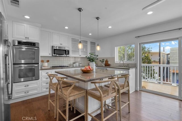 kitchen with visible vents, decorative backsplash, white cabinetry, and stainless steel appliances