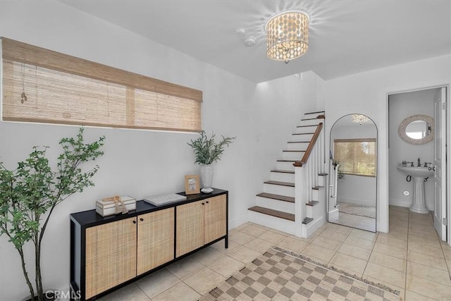 entrance foyer with stairway, baseboards, an inviting chandelier, and light tile patterned flooring