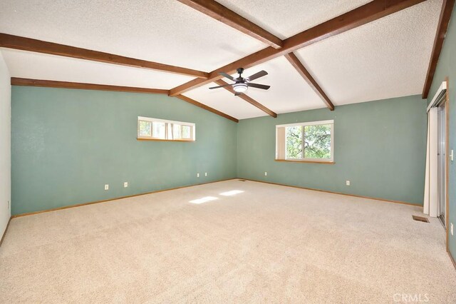 unfurnished room featuring vaulted ceiling with beams, a ceiling fan, a textured ceiling, and carpet flooring