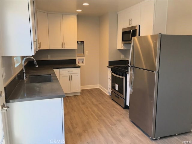 539 E 223rd St, Carson, CA 90745 - kitchen featuring appliances with stainless steel finishes, a sink, white cabinetry, baseboards, and light wood-style flooring