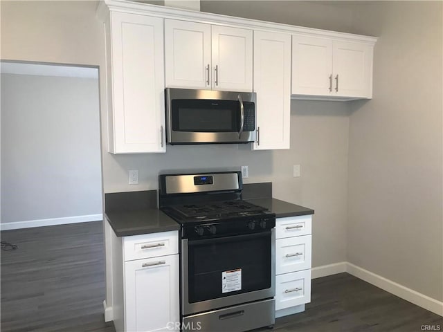 539 E 223rd St, Carson, CA 90745 - kitchen featuring appliances with stainless steel finishes, baseboards, dark wood-style floors, dark countertops, and white cabinetry