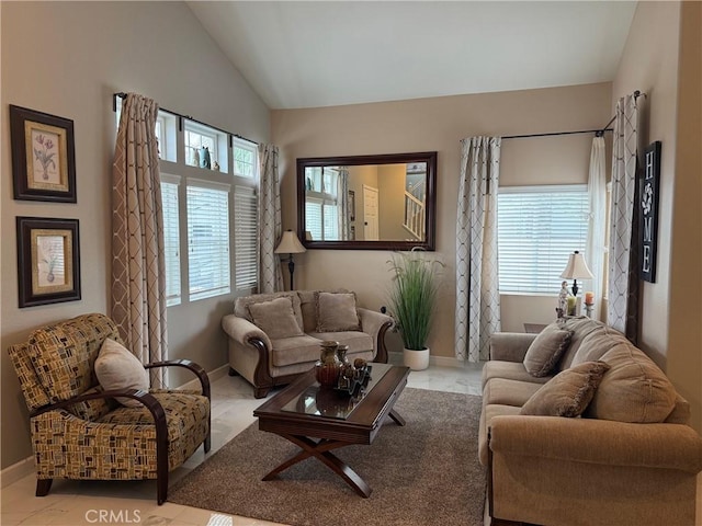 living area featuring baseboards, a wealth of natural light, and vaulted ceiling