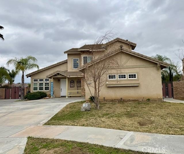 view of front of house with a gate, stucco siding, driveway, and fence
