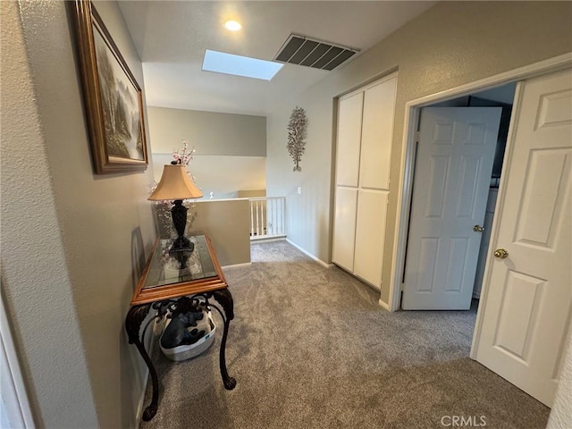 corridor featuring carpet floors, a skylight, and visible vents