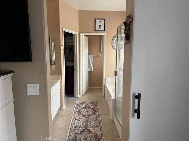 full bath featuring a bath, a walk in closet, tile patterned flooring, and vanity