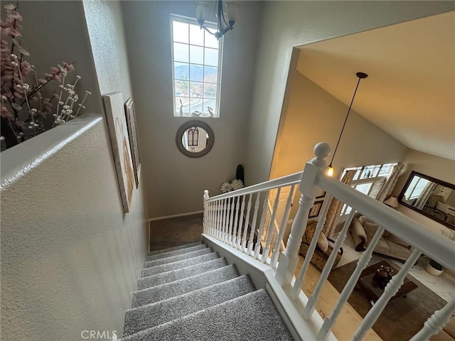 staircase with baseboards, carpet flooring, and a notable chandelier