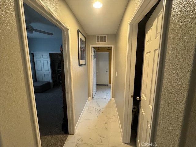 hall with baseboards, visible vents, and marble finish floor