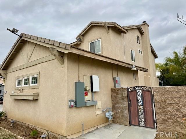 view of side of home featuring fence, a gate, and stucco siding