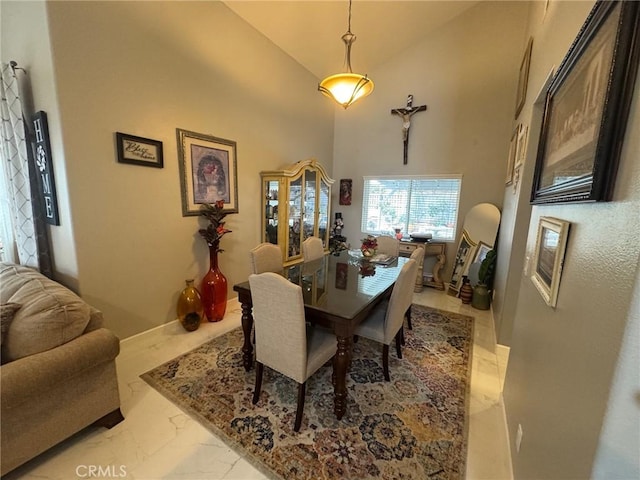 dining space with baseboards, marble finish floor, and high vaulted ceiling